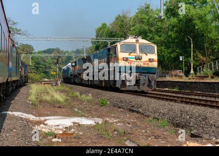 Güterzug Kreuzung 02413 Madgaon - Delhi Hazrat Nizamuddin Rajdhani Special an schönen malerischen Pernem Bahnhof auf Konkan Railway. Stockfoto