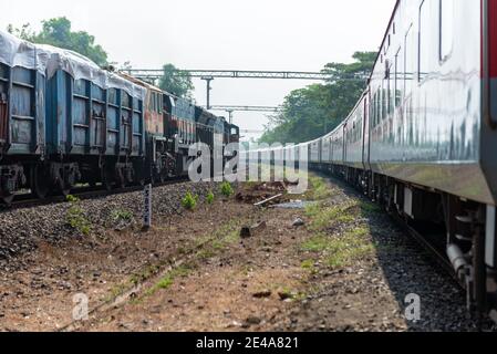 Güterzug Kreuzung 02413 Madgaon - Delhi Hazrat Nizamuddin Rajdhani Special an schönen malerischen Pernem Bahnhof auf Konkan Railway. Stockfoto