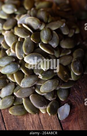 Frische Kürbiskerne auf Holzhintergrund. Geschälte Kürbiskerne. Hintergrund für das Essen. Stockfoto