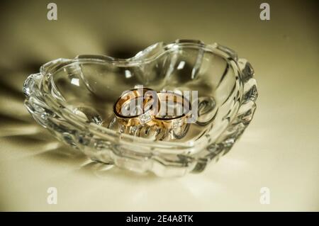Eheringe in einer Kristallvase in Form eines Herzens. Stockfoto