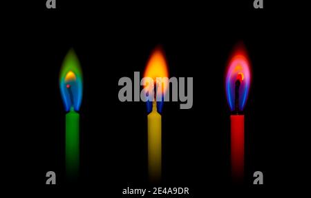 Drei bunte brennende Kerzen leuchten auf dem schwarzen Hintergrund Stockfoto