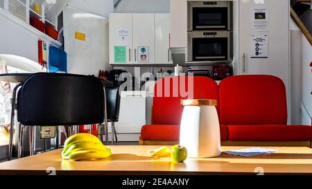 Ein leeres Lehrerpersonalzimmer in einer Grundschule. Obst auf dem Tisch neben einer Keksdose mit Kaffeemaschine und Mikrowelle in der Küche. Stockfoto