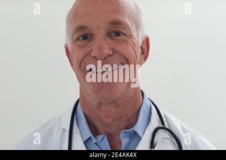 Porträt eines älteren kaukasischen männlichen Arztes, der die Kamera anschaut Und lächelnd Stockfoto