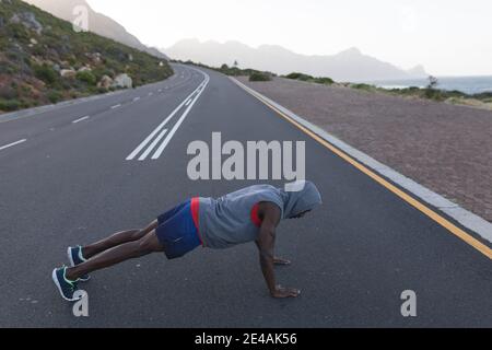 Fit afroamerikanischen Mann in Sportswear tun Liegestütze auf Eine Küstenstraße Stockfoto