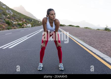 Fit afroamerikanische Frau in Sportswear stehen und ruhen auf Eine Küstenstraße Stockfoto