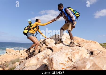 Fit afranamerikanischen Paar trägt Rucksäcke Wandern an der Küste Stockfoto