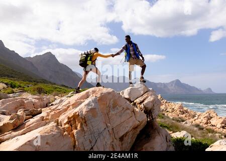 Fit afranamerikanischen Paar trägt Rucksäcke Wandern an der Küste Stockfoto