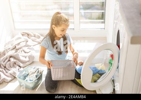 Schöne Kind Mädchen kleinen Helfer hat Spaß und spielen, während die Wäsche zu Hause. Stockfoto