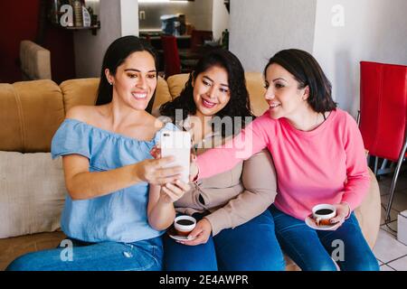 Lateinamerikanische Freundinnen, die ein Selfie-Foto machen und Kaffee trinken Zu Hause in Mexiko-Stadt Stockfoto