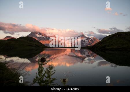 Bergsee im Sonnenuntergang mit Spiegelung und Disteln Stockfoto