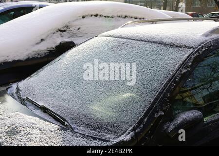 Autos mit einer dicken Schicht gefrorenen Schnees bedeckt. Der Gutsparkplatz im Winter. Stockfoto