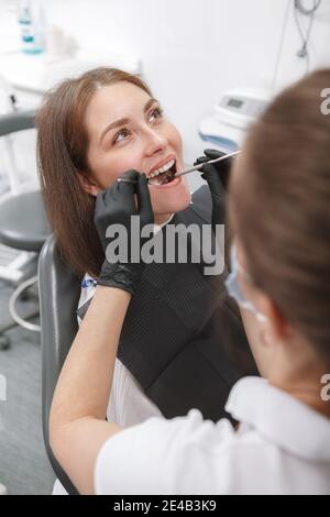 Vertikale Aufnahme einer jungen Frau mit Zahnbehandlung durch Professioneller Zahnarzt Stockfoto