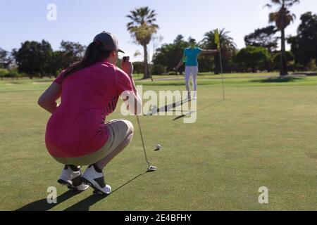 Zwei kaukasische Frauen spielen Golf, eine hockt, bevor sie ein Schuss auf das Loch Stockfoto