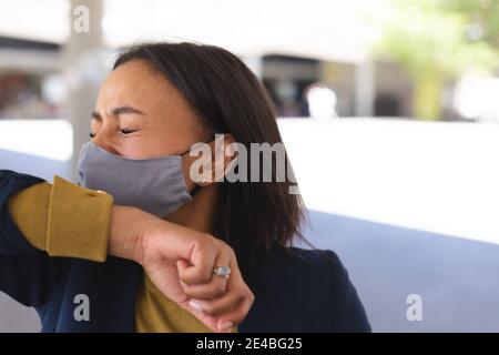 afroamerikanische Frau trägt Gesichtsmaske Niesen auf ihrer Hand auf der Straße. Lifestyle Leben während Coronavirus covid 19 Pandemie. Stockfoto