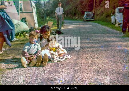 Teenager Zigeunermädchen und zwei kleine Kinder sitzen am Straßenrand. La Roque-sur-Cèze, Gard, Frankreich in den frühen sechziger Jahren. Stockfoto