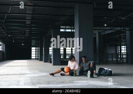 afroamerikanischer Mann und Frau sitzen in leerem Stadtgebäude Und Ruhe nach dem Basketball spielen Stockfoto