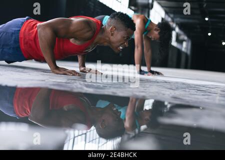 afroamerikanischer Mann und Frau tragen Sportkleidung tun Push Ups in leerem Stadtgebäude Stockfoto