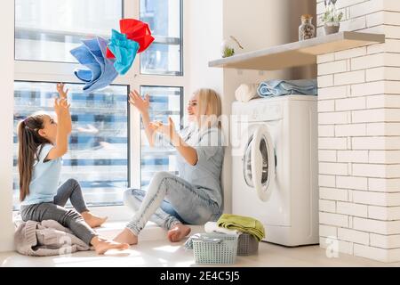 Familie Mutter und Kind Mädchen kleinen Helfer in Waschküche In der Nähe von Waschmaschine und schmutzige Kleidung Stockfoto