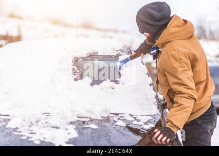 Mann klaren Schnee aus dem Auto mit Reinigungswerkzeug Stockfoto