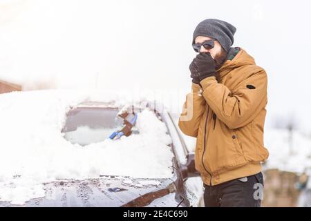 Mann klaren Schnee aus dem Auto mit Reinigungswerkzeug Stockfoto