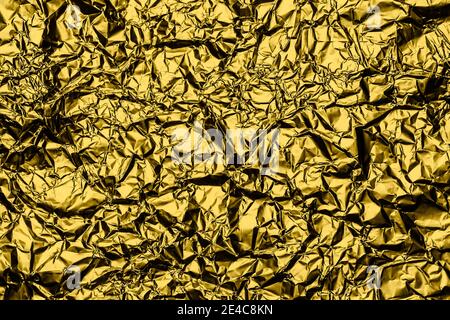 Gelber goldener Folienhintergrund mit glänzend zerknittert Oberfläche für Textur Hintergrund. Schillernde Oberfläche zerknittert Folie. Stockfoto