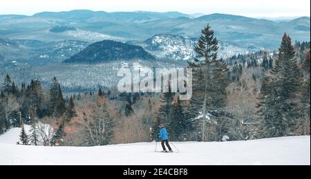 Skihang Blick auf Berggipfel Landschaft Frau Skifahren nach unten. Alpin Ski-Skifahrer Reiten weißen Pulverschnee Piste bei kaltem Wetter auf idyllische Wald Natur Stockfoto