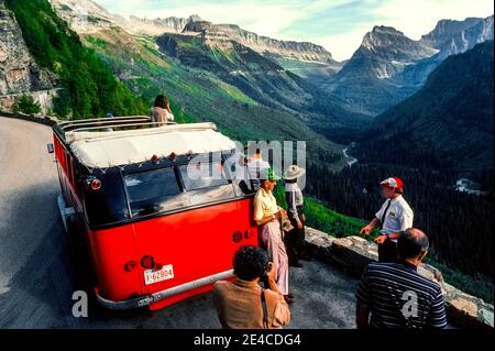 Dieser rote Reisebus aus den 1930er Jahren verfügt über ein rollstuhlgerolltes Segeltuchdach, das sich öffnet, um Touristen bei malerischen Ausflügen entlang der Going-to-the-Sun Road im Glacier National Park im Nordwesten von Montana, USA, einen Panoramablick auf die atemberaubenden Berggipfel zu bieten. Das 17-Personen-Fahrzeug gehört zu den 33 identischen Bussen des Parks, die als Red Jammers bekannt sind, weil ihre Fahrer beim Doppelschalten der Schaltgetriebe auf den steilen Bergstraßen lautstark die Gänge „verklemmen“. Alle diese historischen White Motor Company No. 706 Modelle wurden in ihrem ursprünglichen Aussehen restauriert. Stockfoto