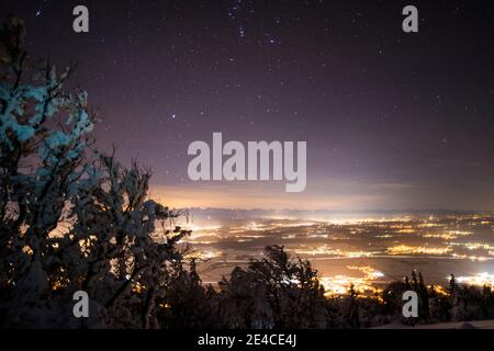 Weihnachtsstimmung, frisch verschneite Landschaft unter dem Sternenhimmel, Lichter im Tal Stockfoto