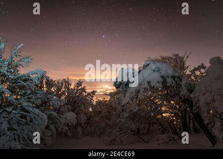 Weihnachtsstimmung, frisch verschneite Landschaft unter dem Sternenhimmel, Lichter im Tal Stockfoto