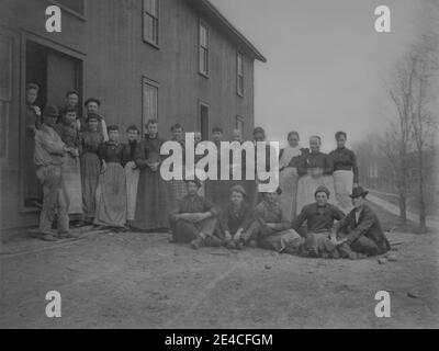 Amerikanisches Archiv monochromes Porträt einer Gruppe von Mitarbeitern oder Arbeitern außerhalb eines Klapptafelgebäudes namens Osburn's Dryer. Aufgenommen im späten 19. Jahrhundert in Port Byron, NY, USA Stockfoto