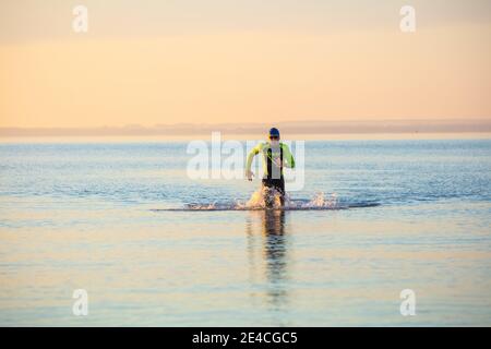 Man 50 plus fit, mit einem Neoprenanzug im Meer. Triahlon-Trainingsmorgen in der Ostsee. Stockfoto