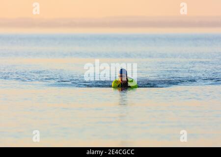 Man 50 plus fit, mit einem Neoprenanzug im Meer. Triahlon-Trainingsmorgen in der Ostsee. Stockfoto