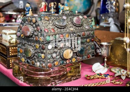 Eiserne Brust voller Steine und Juwelen auf einem Tisch. Es gibt goldene Stücke zusammen und andere Objekte. Stockfoto