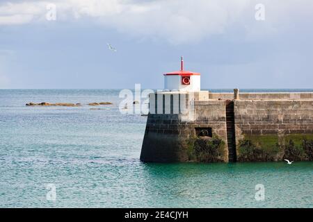 Sturmwolken ziehen über die mächtige Mauer des Barfleur Hafens. Möwen fliegen herum. Cotentin Peninsula, Normandie, Frankreich Stockfoto