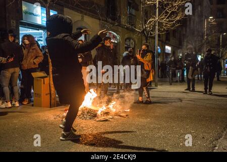 Barcelona, Spanien. Januar 2021. Ein Protestler, der während der Demonstration um ein Lagerfeuer tanzt. Die Wohnungsunion des Viertels Raval von Barcelona hat eine Demonstration aufgerufen, um Lösungen des stadtrates für Gebäude mit Bewohnern zu fordern, die unter Strom- und Wasserkürzungen leiden. Kredit: SOPA Images Limited/Alamy Live Nachrichten Stockfoto