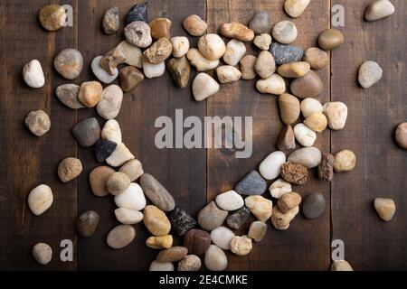 Love Konzept Bild von Herz Form Rahmen aus runden Kieselsteine auf Holzhintergrund Stockfoto