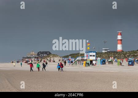 Europa, Deutschland, Niedersachsen, Nordsee, Ostfriesische Inseln, Nationalpark Wattenmeer, Borkum, Südstrand, Elektrischer Leuchtturm, Restaurant heimische Liebe, bei Gegenwind gehen die Menschen in einen Sturm Stockfoto