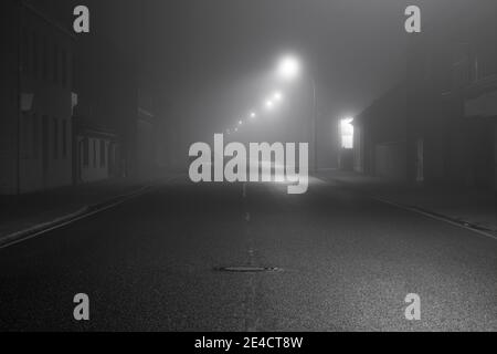 Nebel in den Straßen der Stadt Luckenwalde ,at Nacht in der Jueterboger Straße, geparkte Autos am Straßenrand Stockfoto