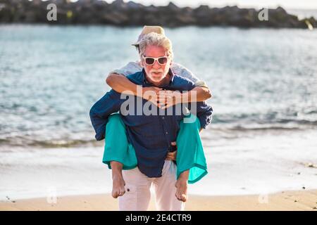 Ältere alte Leute Pärchen haben Spaß zusammen am Strand Im Sommerurlaub Urlaub - Tourist reifen Mann und Frau Sich gegenseitig tragen und die Meeresreise genießen Stockfoto