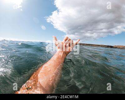 Mann reicht das Surfschild hallo aus dem blauen Himmel meerwasser mit Küste und schönem Himmel im Hintergrund - Konzept von Menschen und Sommerurlaub Stockfoto