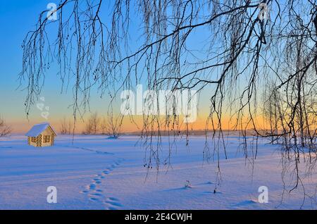 Holzspielzeughaus auf verschneiten Winterhintergrund im warmen Licht des Sonnenaufgangs. Konzept für Neujahr und Weihnachtsferien. Warm, gemütlich, liebevoll, schützend Haus con Stockfoto