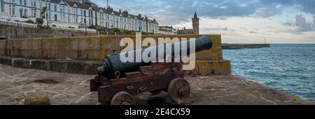 PORTHLEVEN, CORNWALL, UK - 10. JUNI 2009: Panoramablick auf das alte Marinegewehr am Hafenkai mit Blick auf das Dorf, Pier und Pier Church Stockfoto