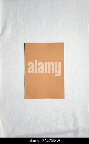 Kamelfarbenes quadratisches leeres Papierblatt auf weißem Leinen. Speicherplatz kopieren. Taktiler flacher Hintergrund mit großem Kopierplatz. Bio-Design. Pastellfarben. V Stockfoto
