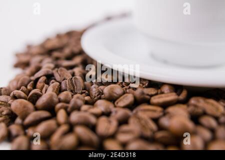 Eine geröstete Kaffeebohnen in der Nähe einer Untertasse aus einer Tasse Kaffee Stockfoto