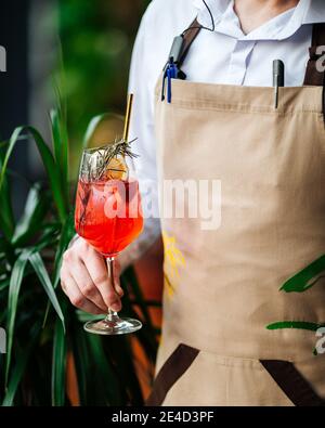 Kellner hält ein Glas aperol Spritz Cocktail mit einem Stroh Stockfoto