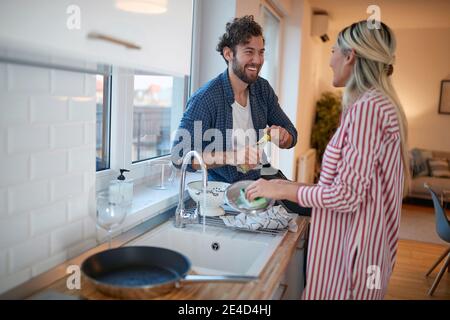 Glückliches Paar macht das Geschirr zusammen in der Küche Stockfoto