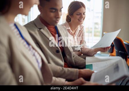 Multiethnische Gruppe von jungen Menschen lesen Skripte auf Business-Seminar im Konferenzraum, Austausch von Ideen und Meinungen Stockfoto