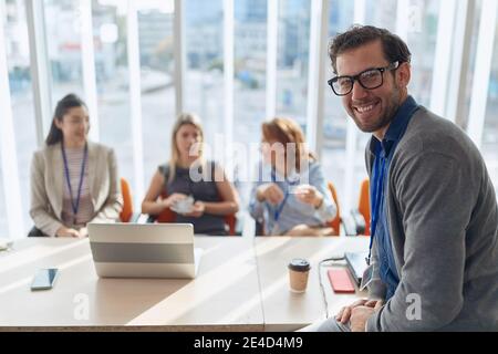 Porträt des jungen kaukasischen Manager bei einem Geschäftstreffen. Blickkontakt, Blick auf die Kamera, lächelnd Stockfoto
