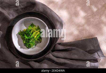Japanischer Salat mit grünen Wakame-Algen auf zwei Tellern und einem Graue Serviette mit Kopierraum Stockfoto