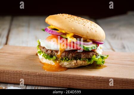 Seitenansicht auf klassischen Burger mit Ei auf dem Holz Platine Stockfoto